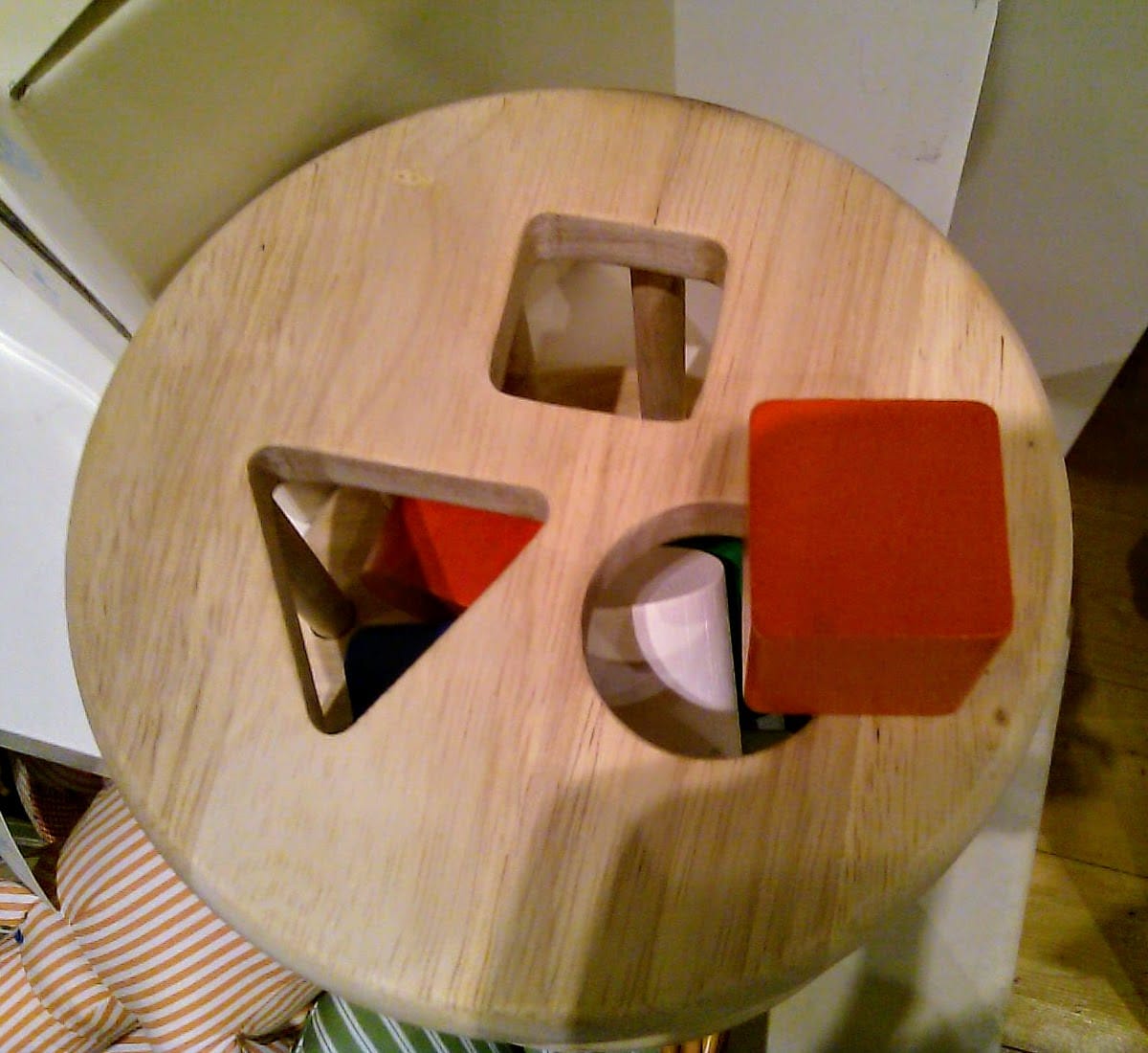 Child's toy with a square peg over a round hole. There is also triangle and square holes.