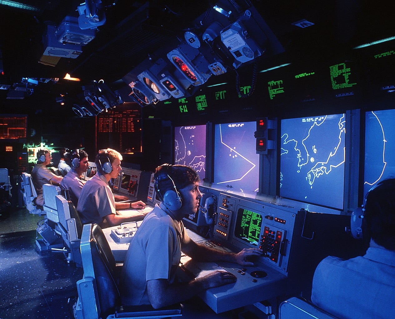 Sailors sitting in front of computerized control consoles.