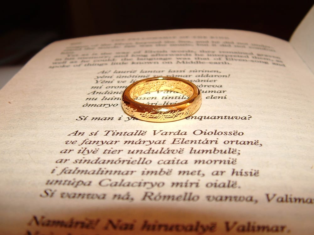 Tolkien's magic golden Ring of Power, enscribed with Elvish words, sitting on a page in book with an Elvish poem.