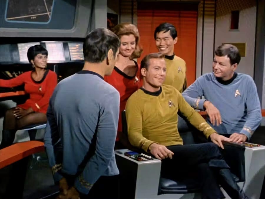 Captain Kirk sitting in his command chair on the bridge of the starship Enterprise, surrounded by crew members.